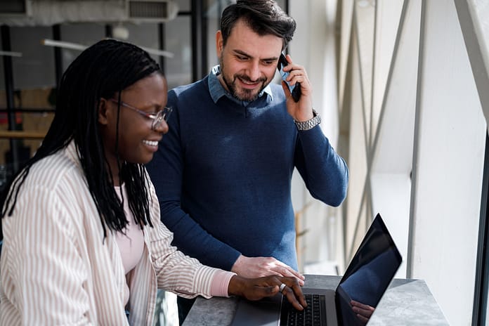 Business discussion at a workspace with people using a laptop and a phone