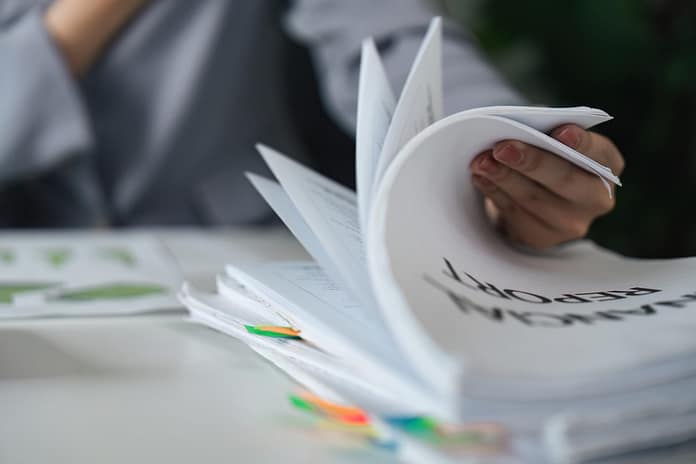 Documentation and Reporting. A professional handling multiple financial reports.