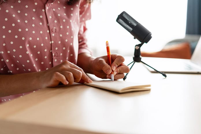 Woman Taking Notes During Podcast Recording
