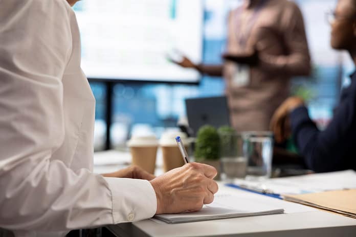 Female investor takes notes during financial projection in a meeting