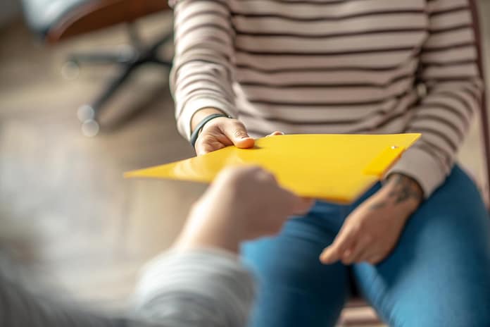 Close up picture of womans hand passing the folder