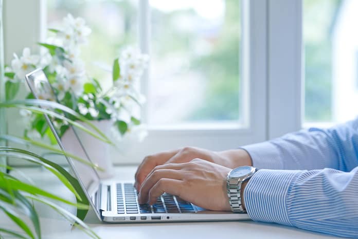 Closeup of man's hands on computer keyboard, working from home